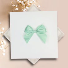 Load image into Gallery viewer, A white square box with a mint green bow on top, placed on a pink background.