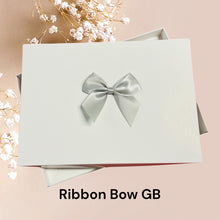 Load image into Gallery viewer, a white box with a silver ribbon bow on it, placed on a pink background.