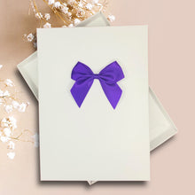 Load image into Gallery viewer, a white card with a purple bow on it, placed on a pink background.