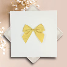 Load image into Gallery viewer, A white square box with a yellow bow tied on top, placed on a pink background.
