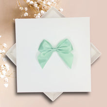 Load image into Gallery viewer, A white square box with a mint green bow on top, placed on a pink background.